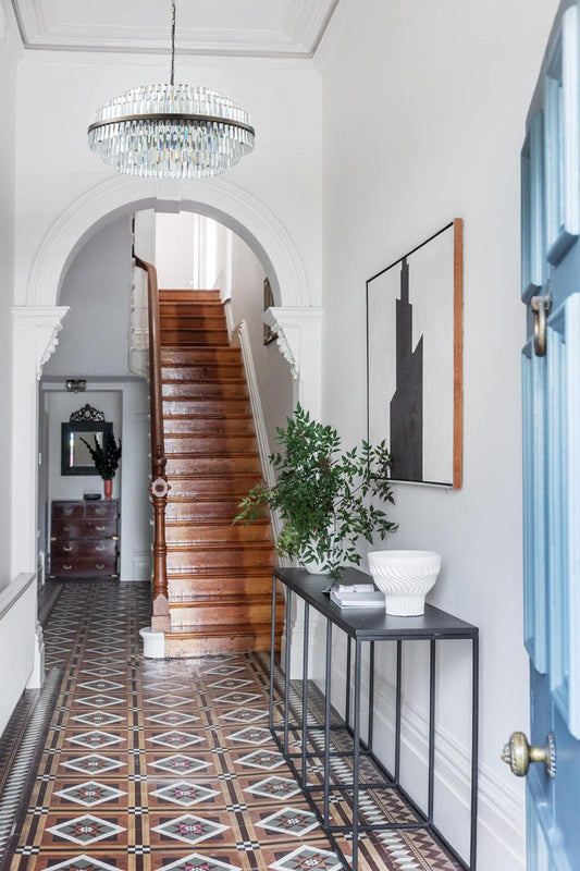 Large glass chandelier with antique brass metalware in the foyer of a 2 story heritage home. 