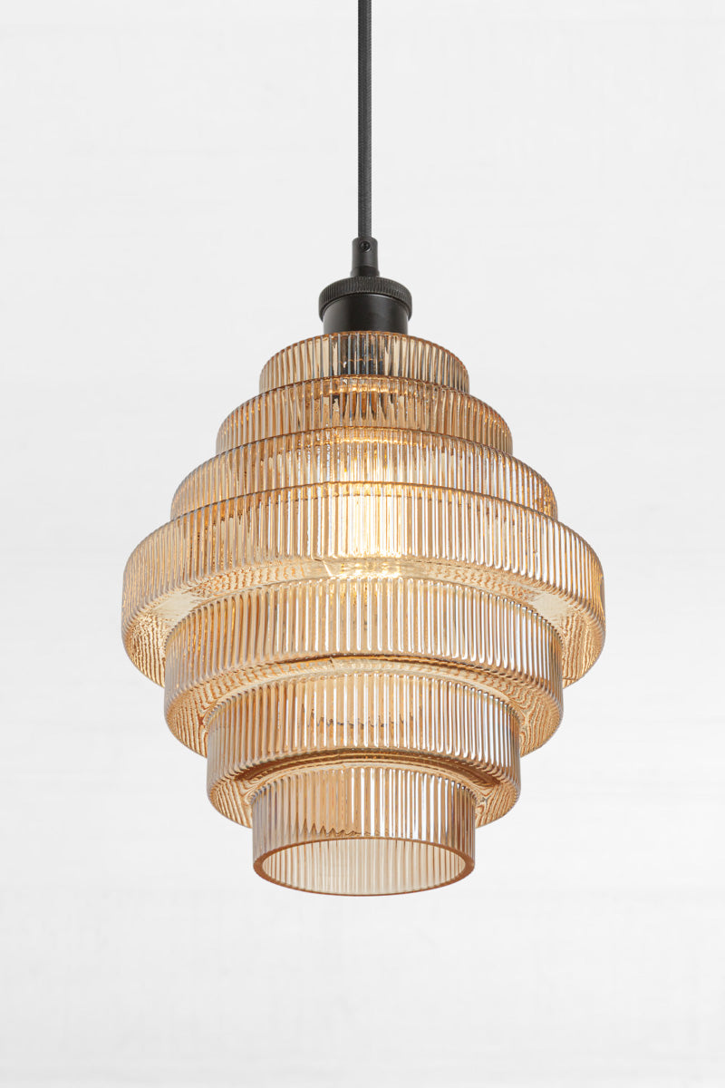 Amber tiered and reeded glass pendant with black lampholder showing open end of shade. 