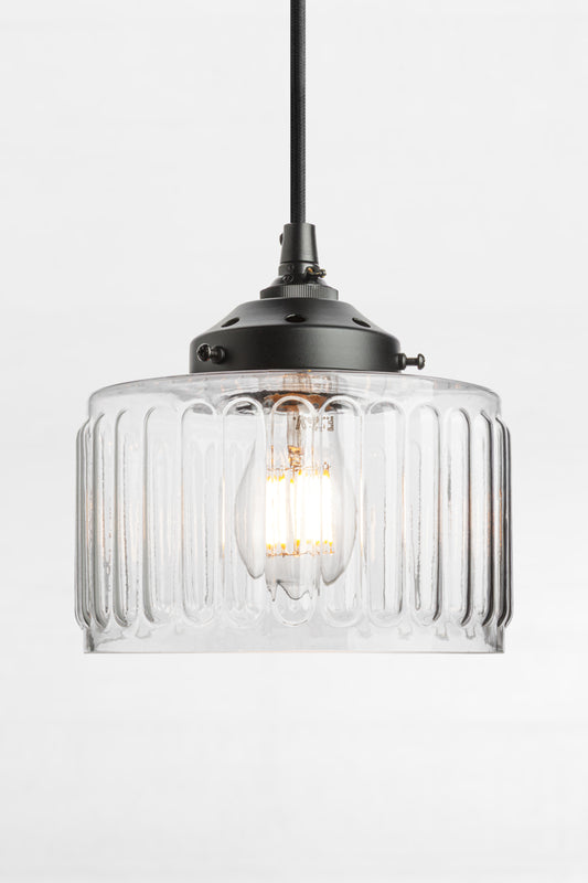 Clear glass shade with vintage flair on a black pendant cord and gallery. 