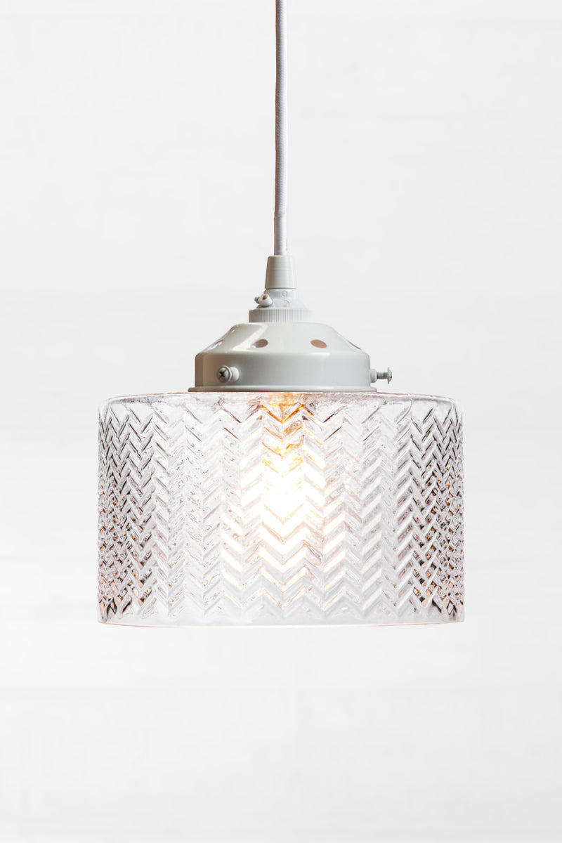 cylindrical shade features a wavey chevron pattern and is on a white cord