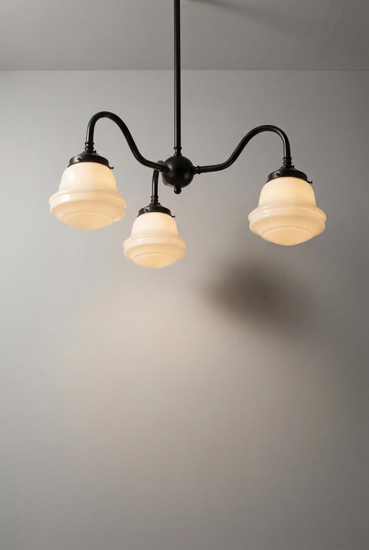 Colton Schoolhouse Gooseneck Chandelier in black with three opal glass shades, illuminated against a neutral wall.