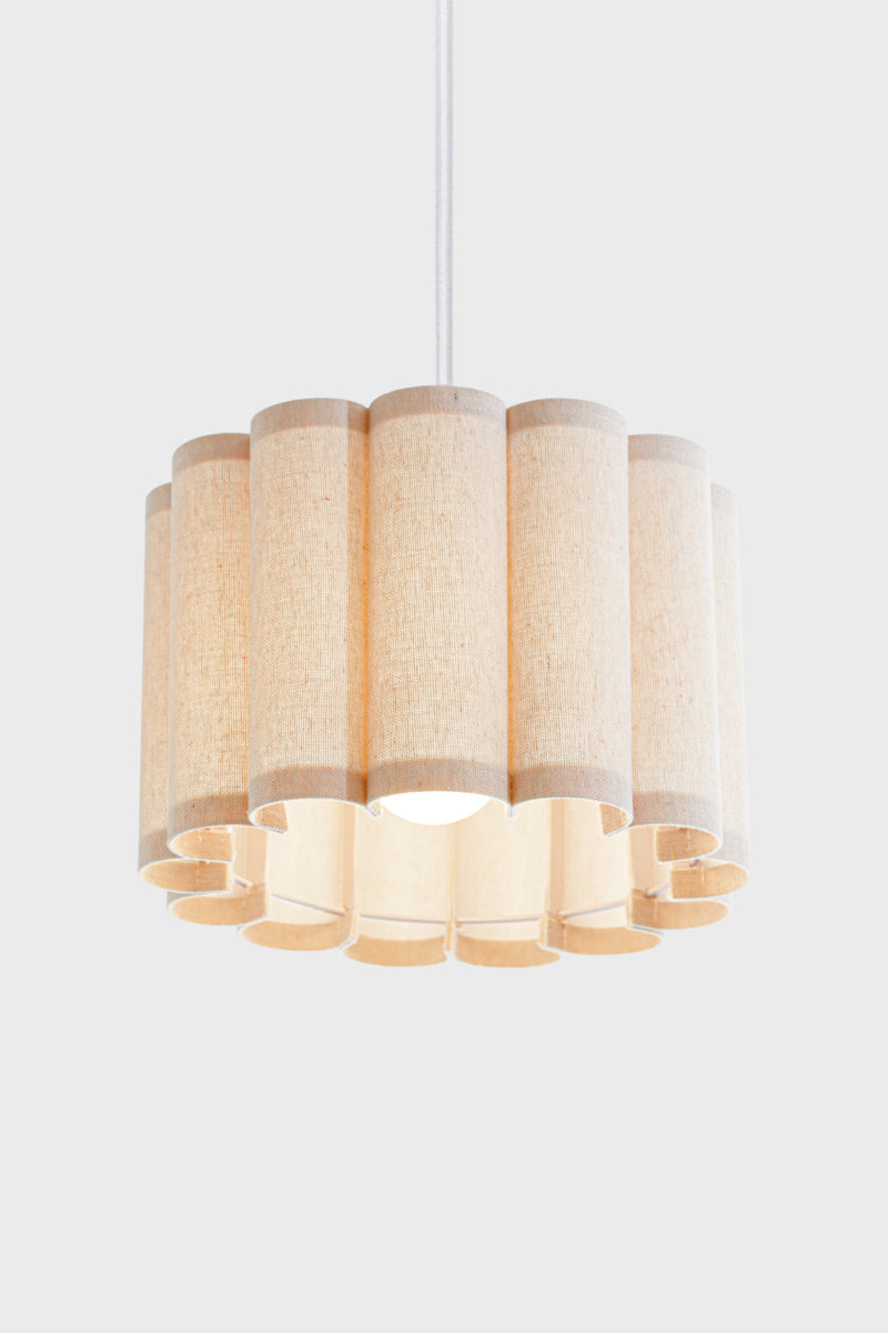 Neutral toned coloured fabric shade with a scalloped silhouette, paired with a white pendant cord an opal bulb. 