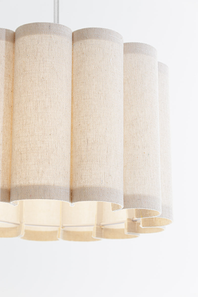 Small fabric scalloped shade with white wire frame paired with a white pendant cord. 
