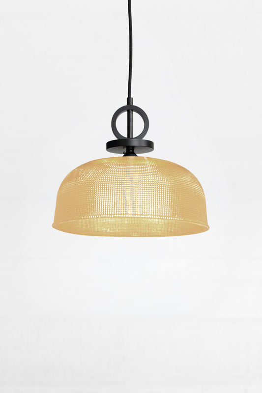 Large amber holopane style shade paired with a black pendant cord with black metal detailing. 