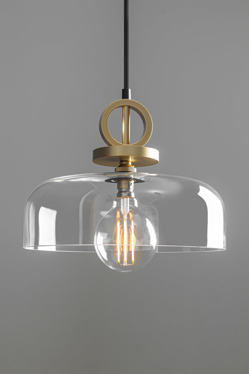 Dixon NYC Glass Pendant Light with gold/brass ring and disc suspension, transparent dome-shaped glass shade and exposed filament bulb.