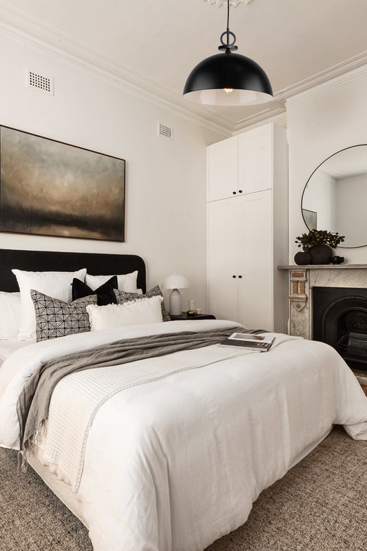 Large black dome pendant light over an elegant monochrome bedroom space. 