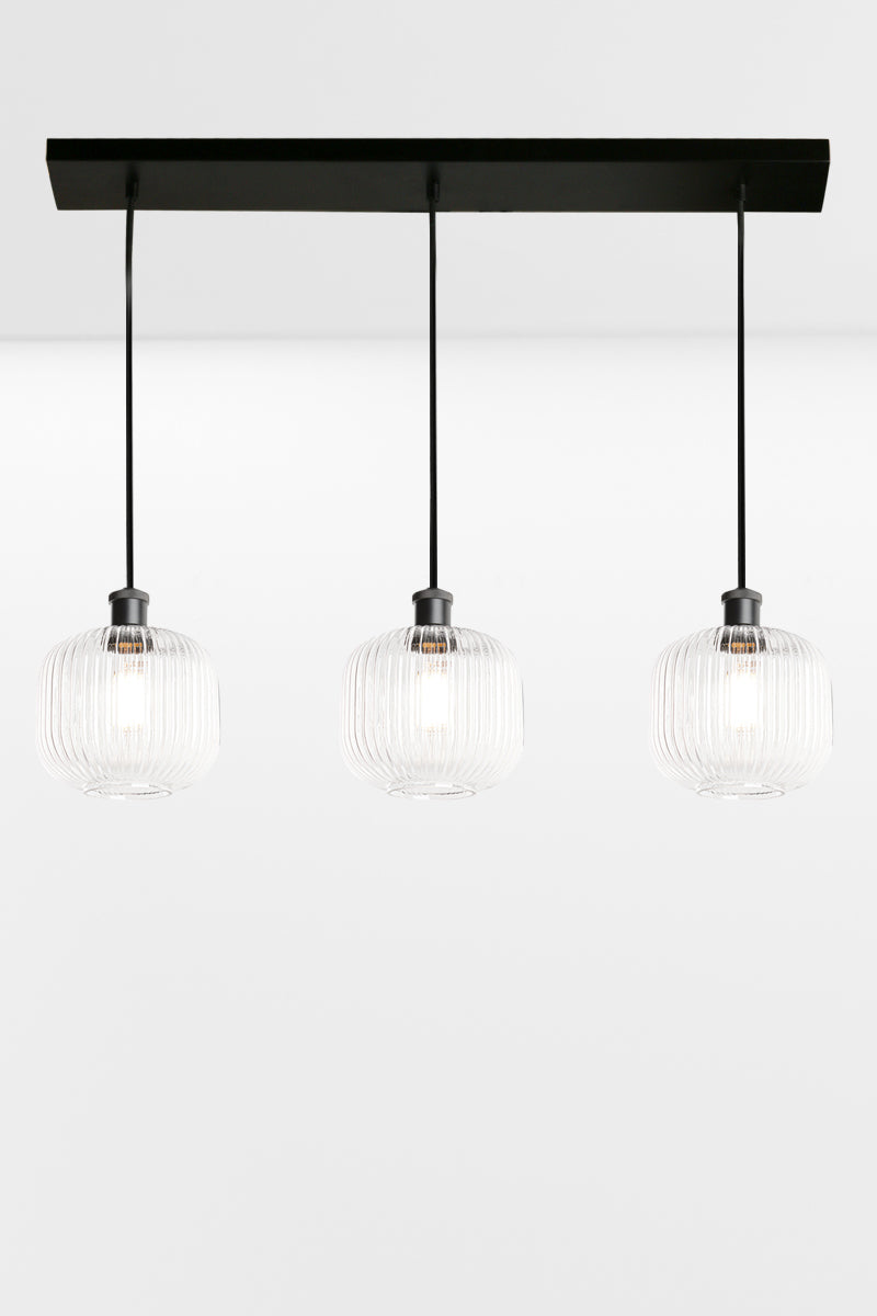 3 light linear multi pendant light with clear reeded open glass shades in an even row. 