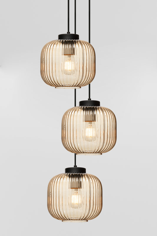 Three drop pendant light with reeded glass shades in amber and black hardware. 