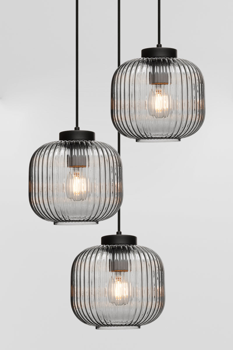 Three drop pendant light with reeded glass shades in grey and black hardware. 