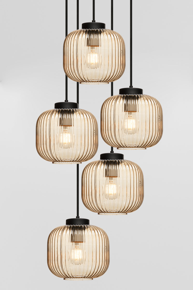 Five drop pendant light with reeded glass shades in amber, paired with black hardware. 