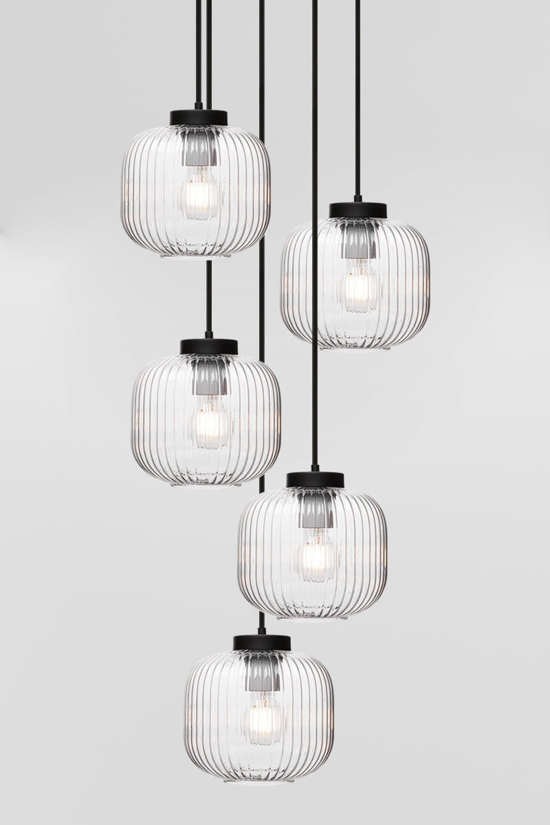 Five drop pendant light with reeded glass shades in clear and paired with black hardware. 