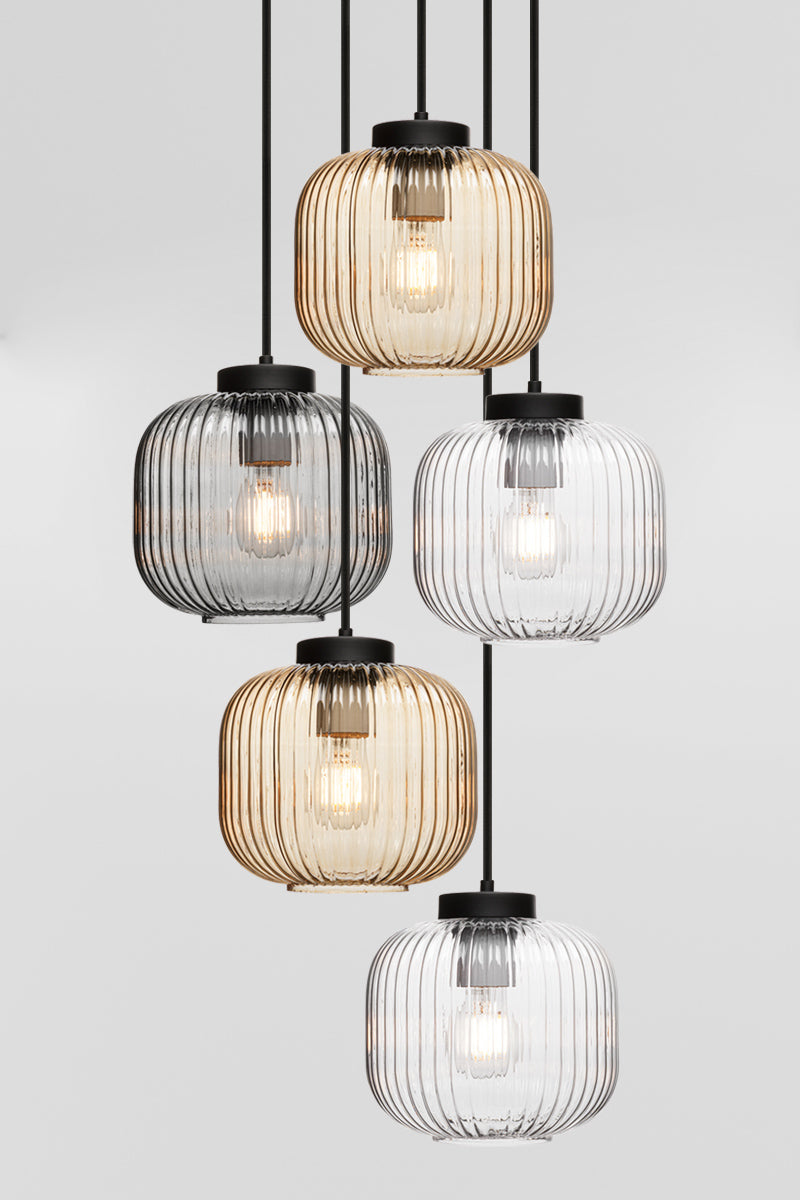 Five drop pendant light with reeded glass shades in amber, clear and grey paired with black hardware. 