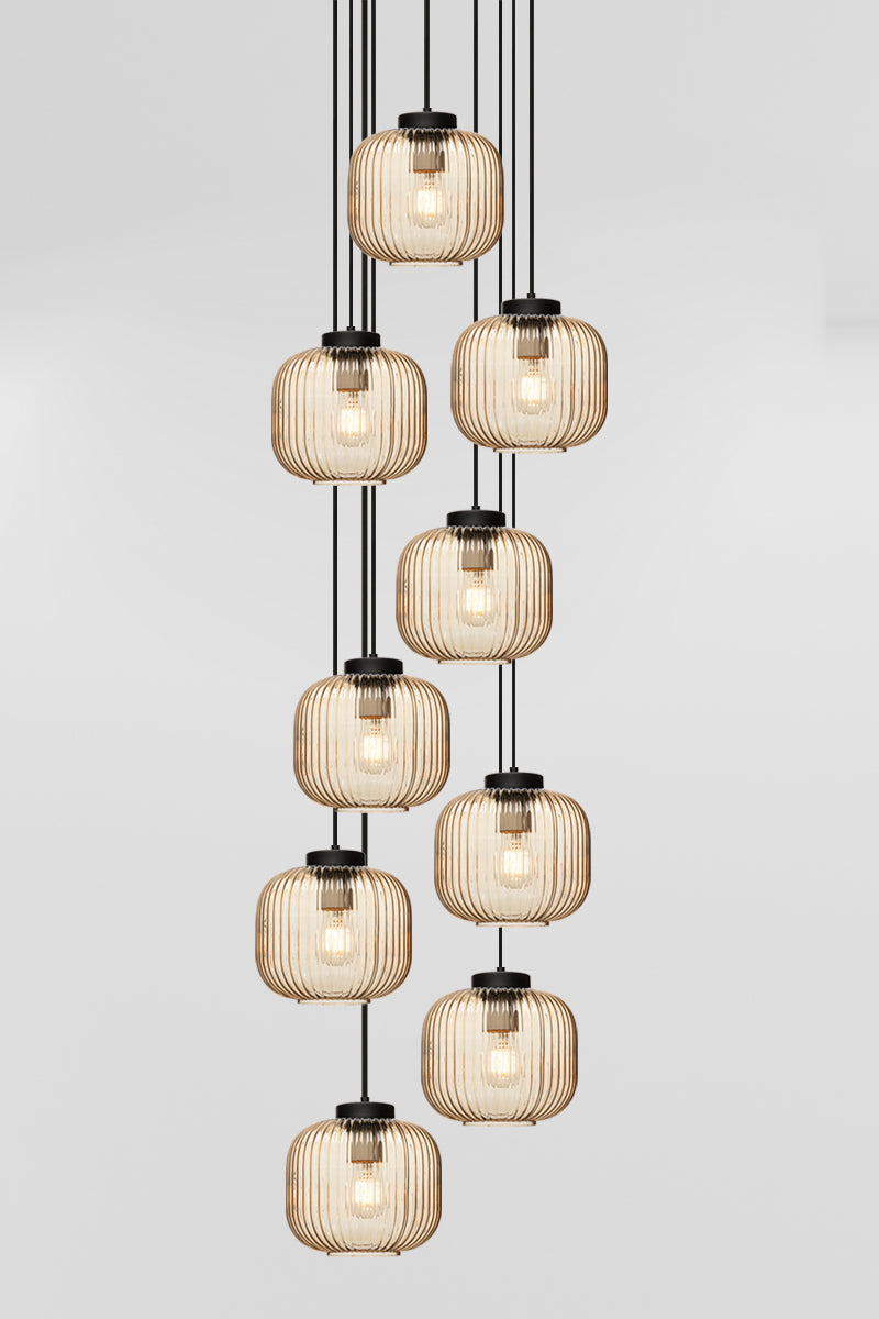 Nine drop pendant light with reeded glass shades in amber, paired with black hardware. 