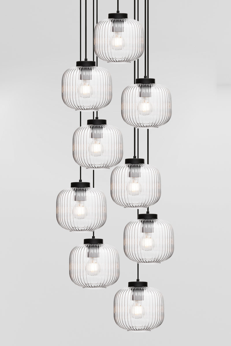 Nine drop pendant light with reeded glass shades in clear, paired with black hardware. 