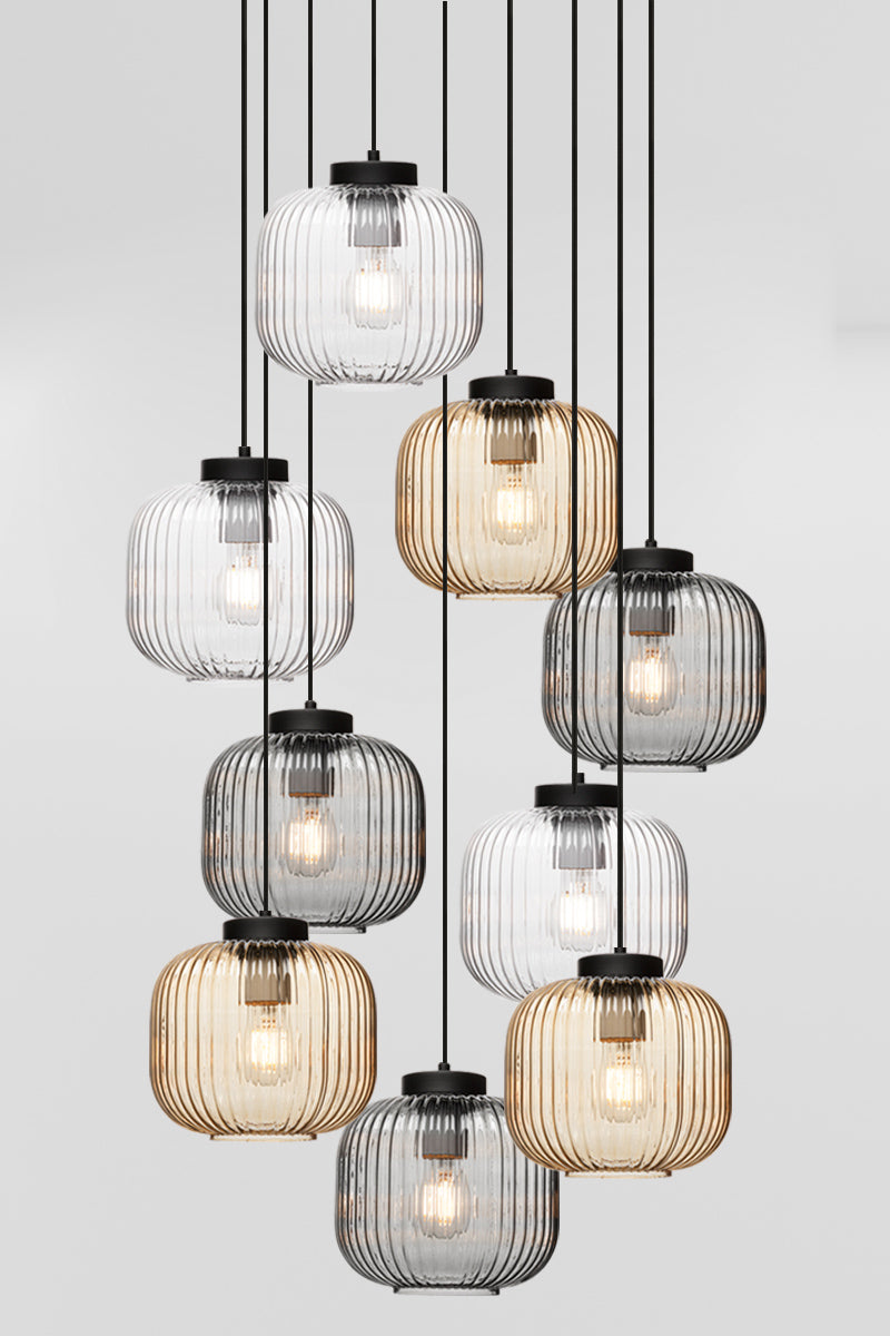 Nine drop pendant light with reeded glass shades in amber, clear and grey, paired with black hardware. 