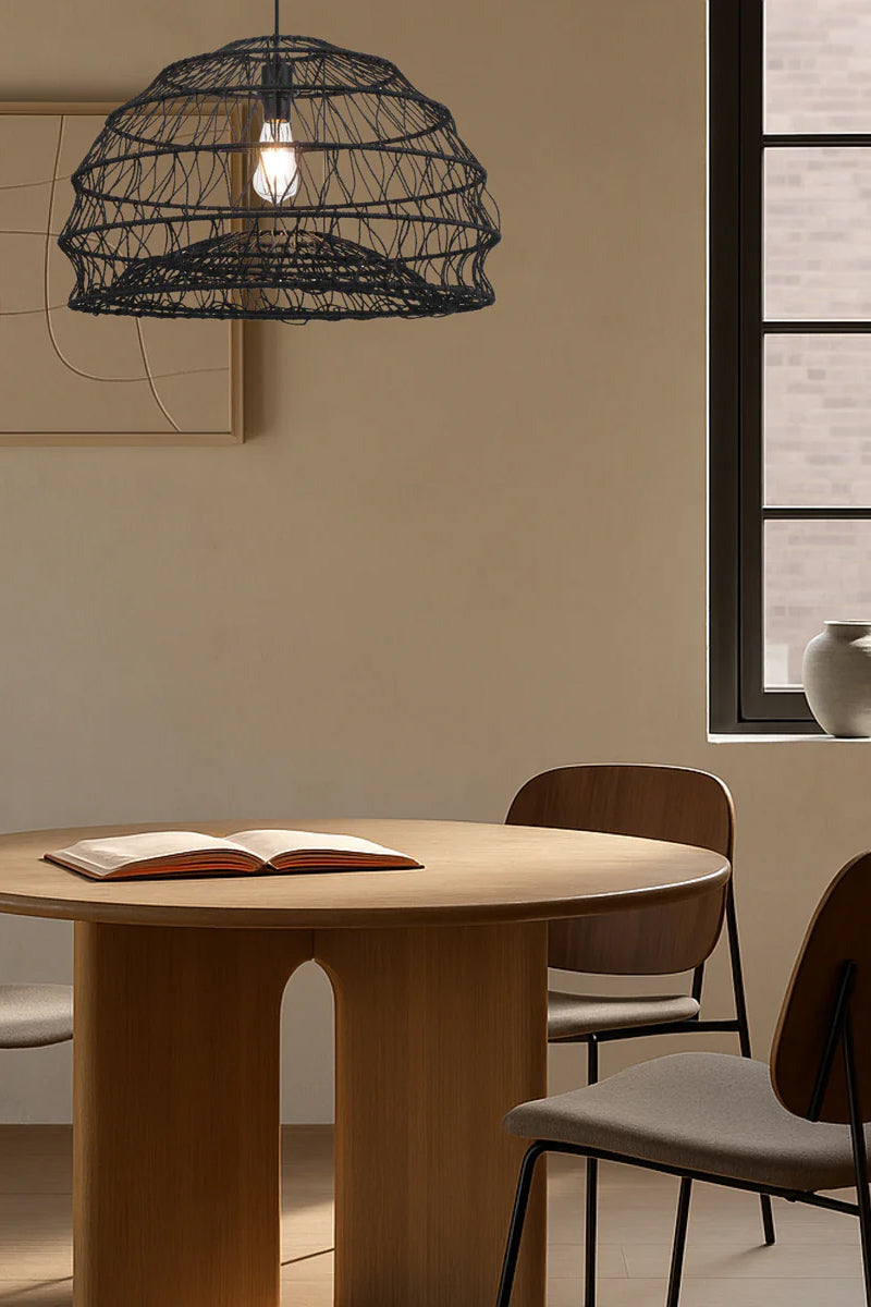 Black woven rattan pendant light styled above dining table in warm modern interior setting