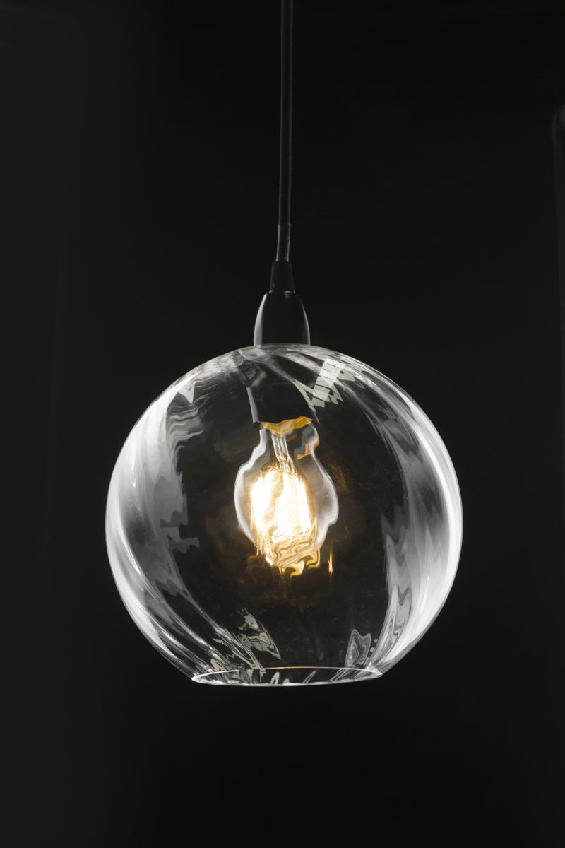 Kansas Glass Pendant Light illuminated against dark background with clear twisted shade and black cord