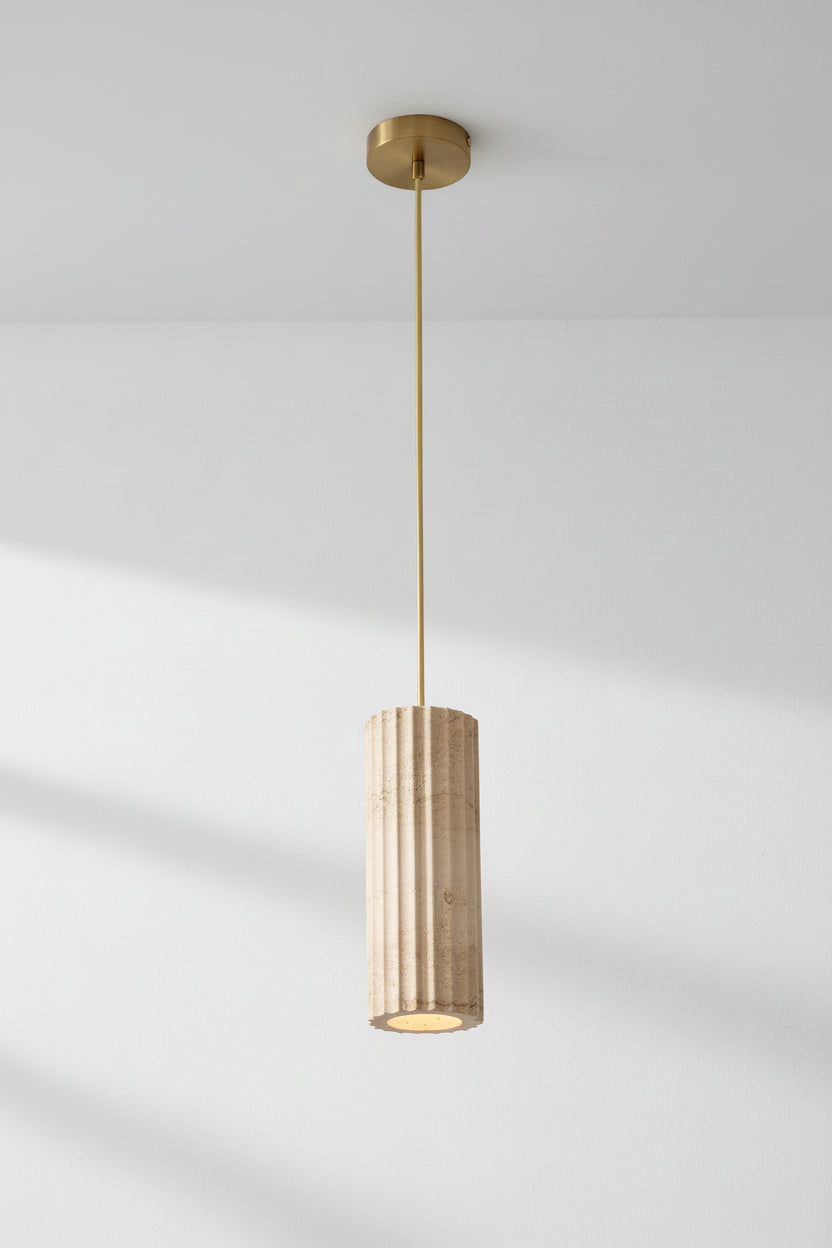 Pendant light made up of a travertine pendant light with subtle fluting across the natural finish, paired with gold fabric cord and gold hardware. 
