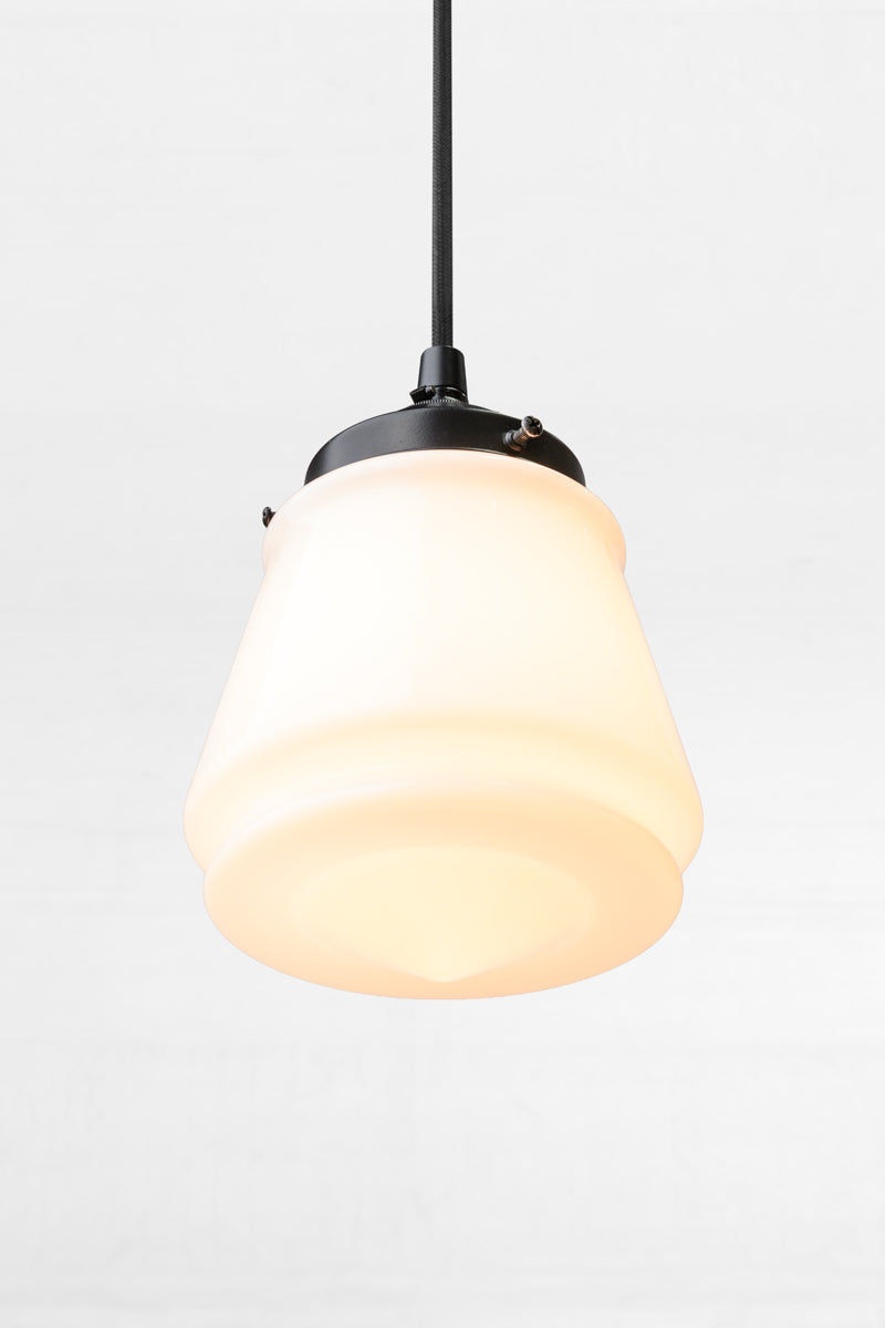 Tilted view of the opal glass Mae Deco Glass Shade paired with a black gallery and cloth cord.