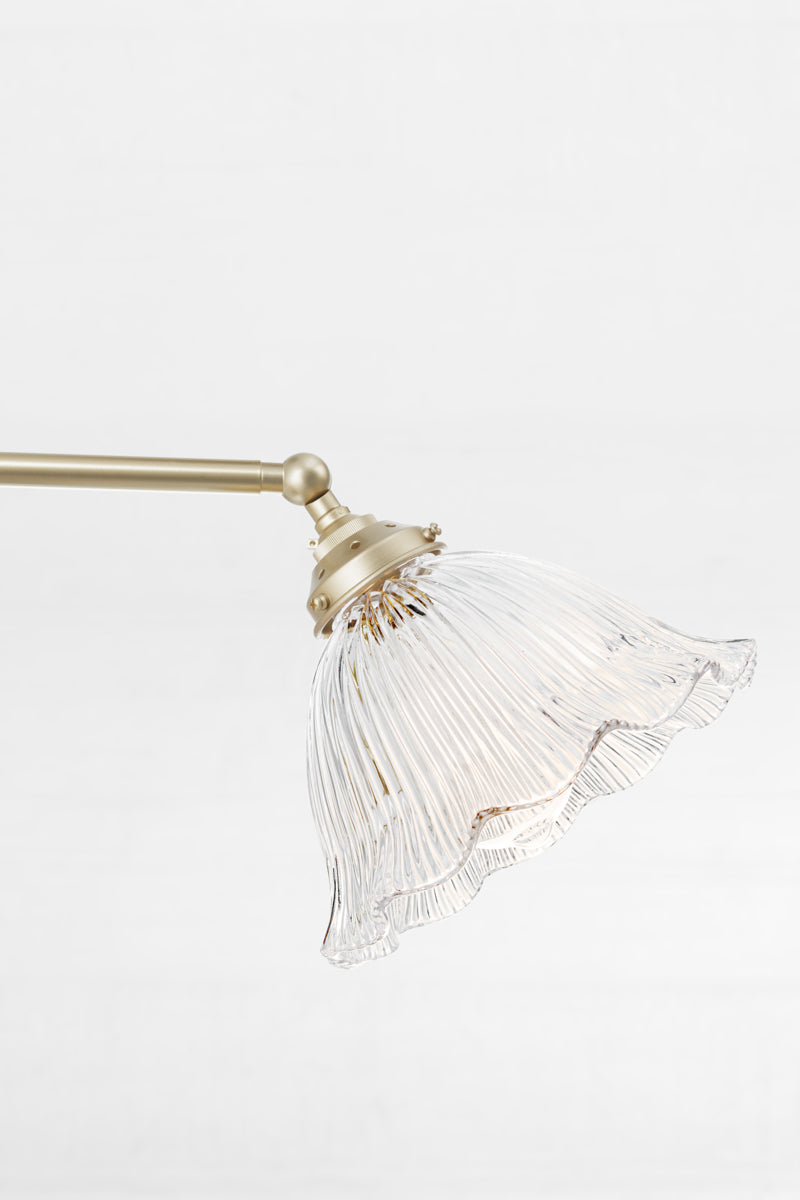 Tilted gold brass chandelier arm with clear glass reeded shade. 