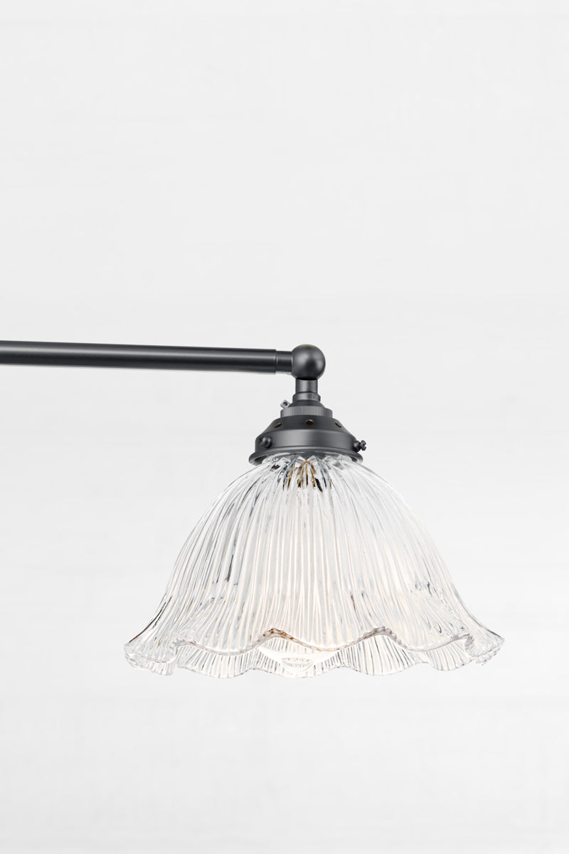 Close up of the Black steel adjustable lampholder with a clear glass shade featuring reeded detailing and a frilled edge