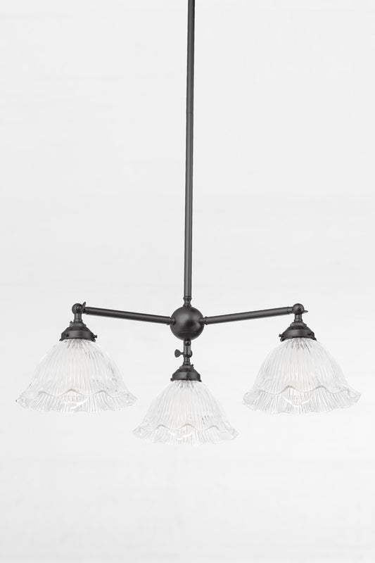 Reeded clear glass shades with a frilled edge, paired with a black 3 arm chandelier with adjustable lampholders.
