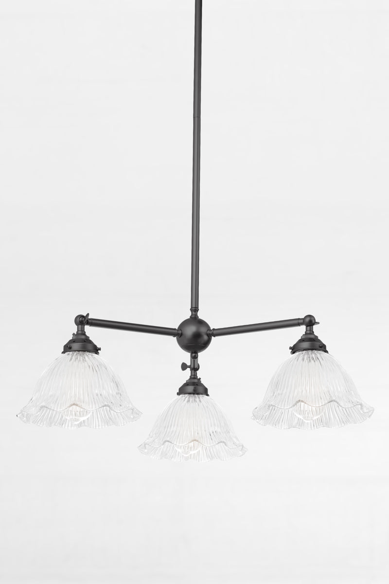 Reeded clear glass shades with a frilled edge, paired with a black 3 arm chandelier with adjustable lampholders.