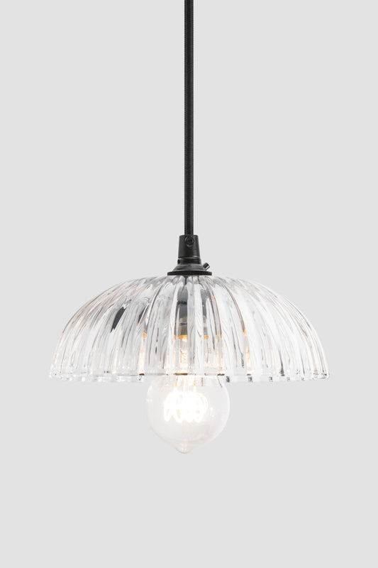 Deloraine clear glass pendant light with broad tapered ridges suspended from a black cloth cord.