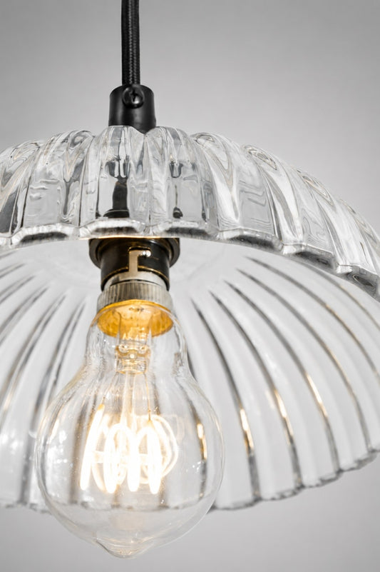Close up illuminated view of the Deloraine pendant light showing shimmering reflections through the clear ridged glass shade.