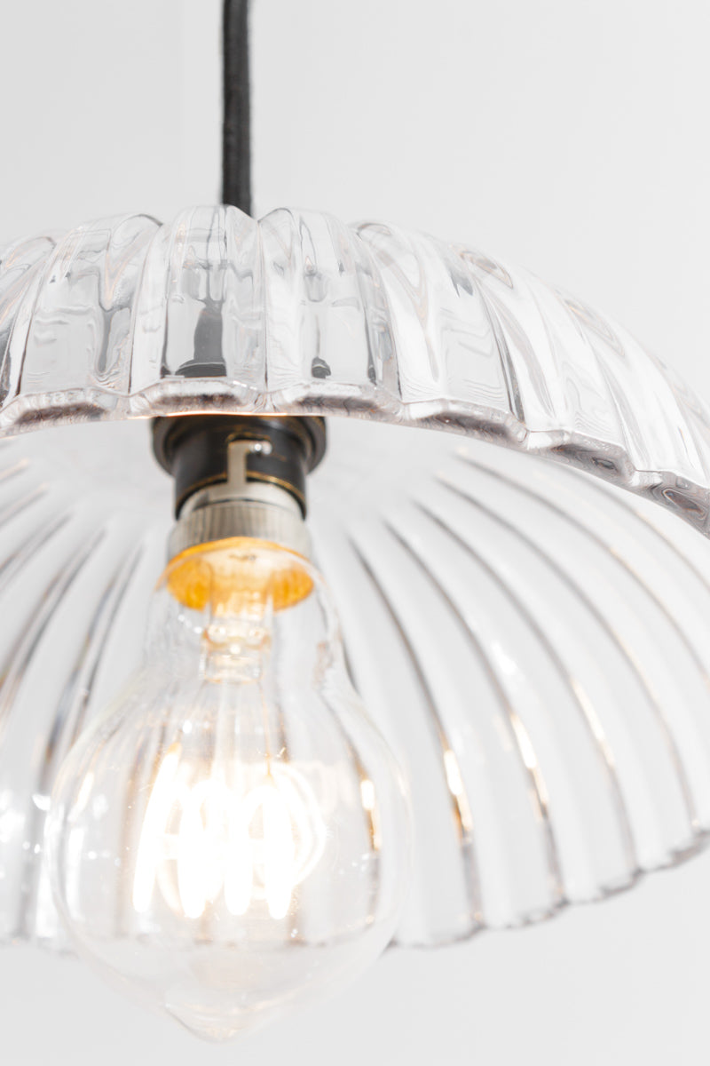 Close up detail of the Deloraine clear pressed glass pendant shade with illuminated filament bulb and tapered ridge texture.