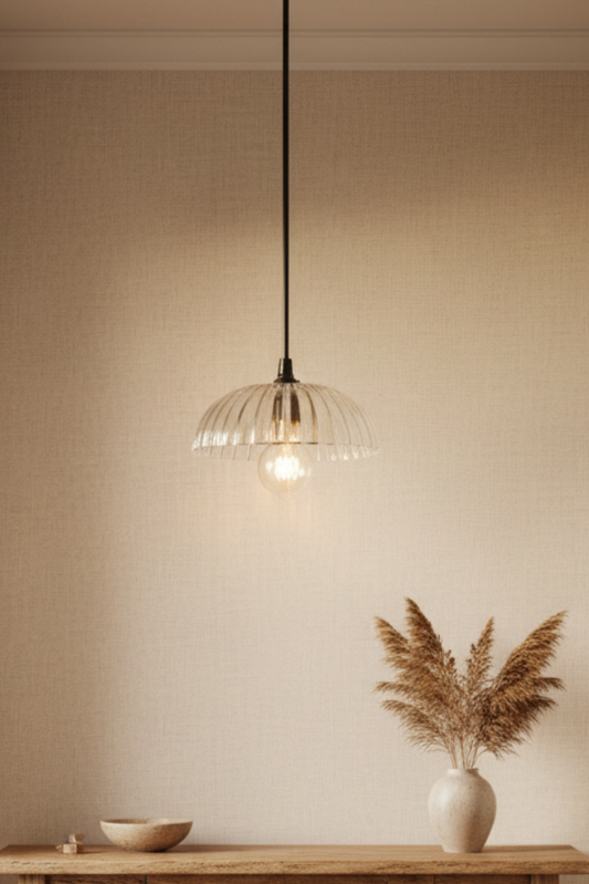 Narrow table against a beige wall with glass pendant light hanging above. Deloraine clear pressed glass shade highlighting broad linear ridges and smooth internal finish.