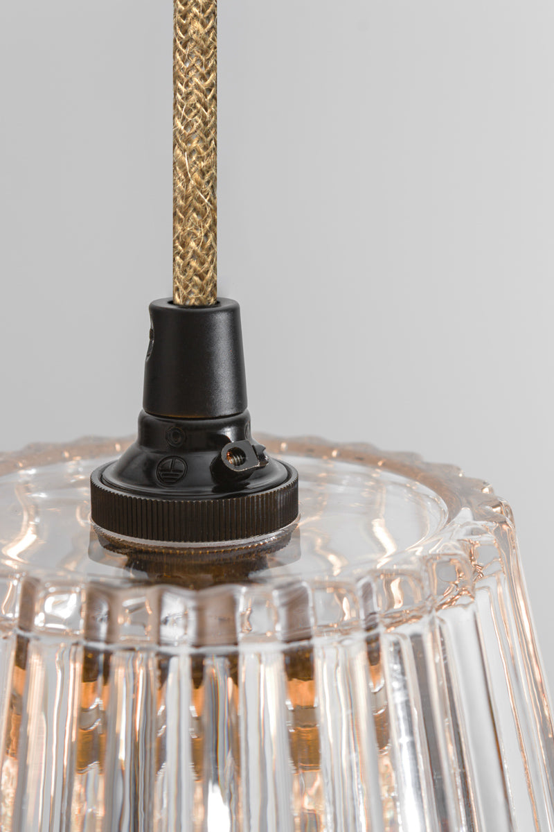 Close-up of a clear glass pendant light with a jute braided cable against a gray background