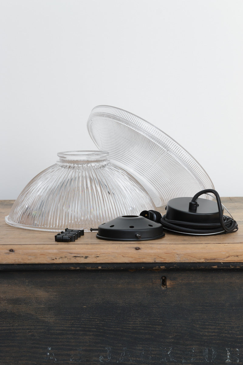 Glass Pendant Light components displayed separately, featuring two textured clear glass shade sections, black retaining clips and matt black suspension hardware on a timber surface.