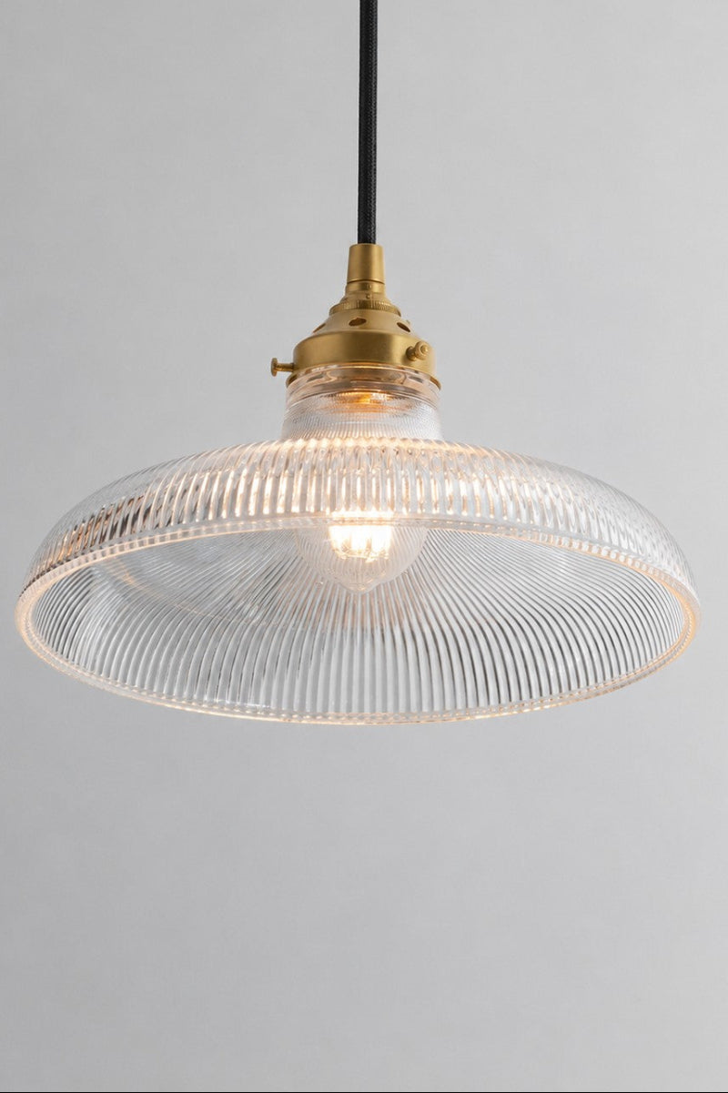 Large clear glass shade with holophane detailing paired with a gold/ brass gallery and black pendant cord. 