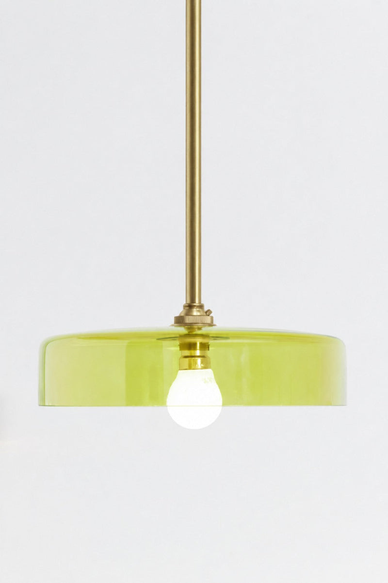 A green glass shade on gold/brass pole pendant  saturating a surface with light without obscuring it 