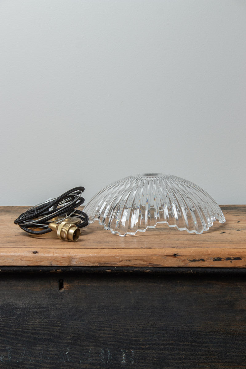 Hepburn clear fluted glass pendant shade displayed on a timber surface with black pendant cord and lampholder