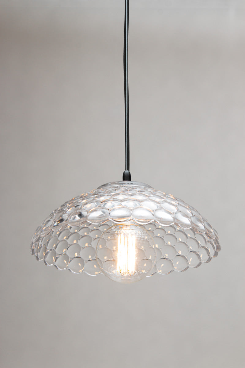 Belrose Glass Pendant Light is a clear glass pendant light with a textured-like pattern and a visible warm light bulb inside, suspended by a black cord