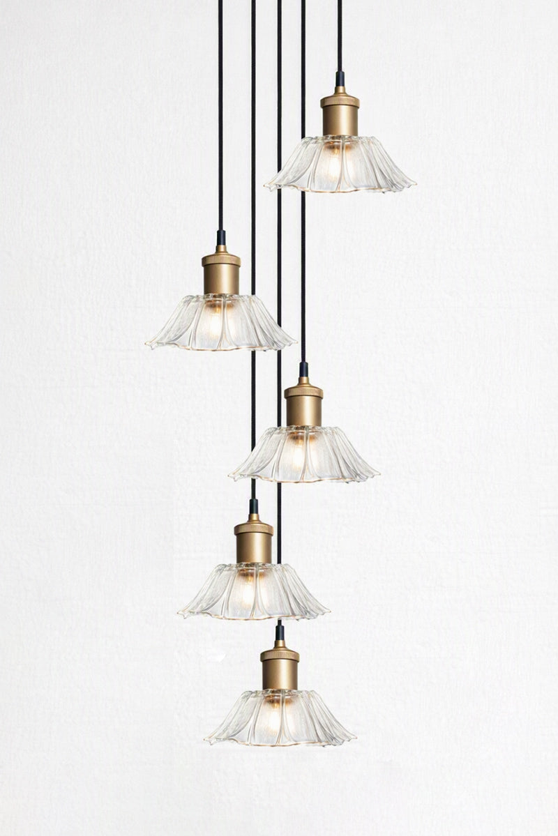 Honfleur Glass Multi Drop Pendant with gold brass cords and five clear fluted glass shades suspended at staggered heights from a black round ceiling rose.