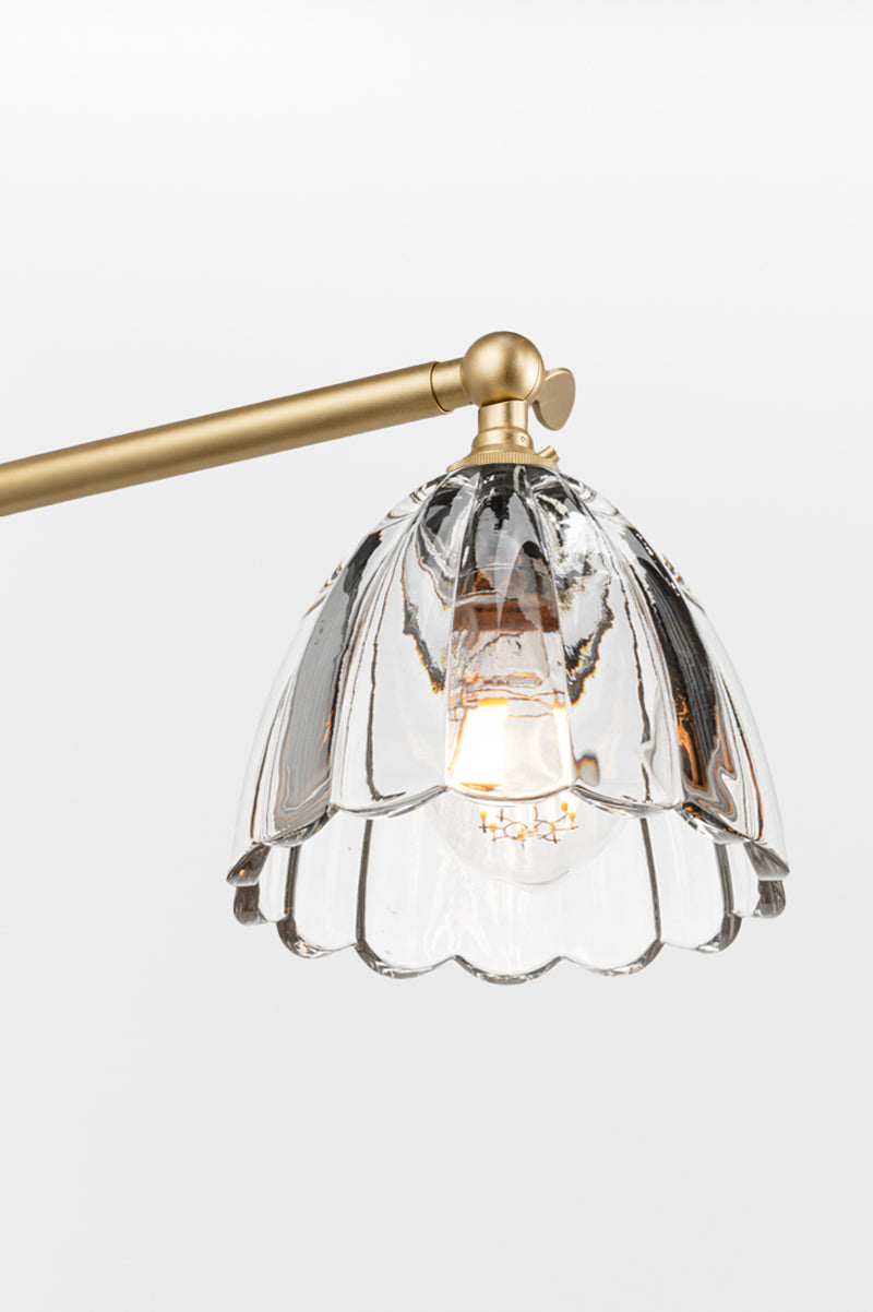 Gold/brass chandelier straight arm with clear glass shade featuring a scalloped edge. 