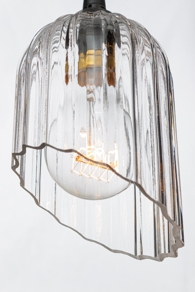 Angled cut, elongated clear glass shade with fluted detailing paired with a clear A60 bulb. 