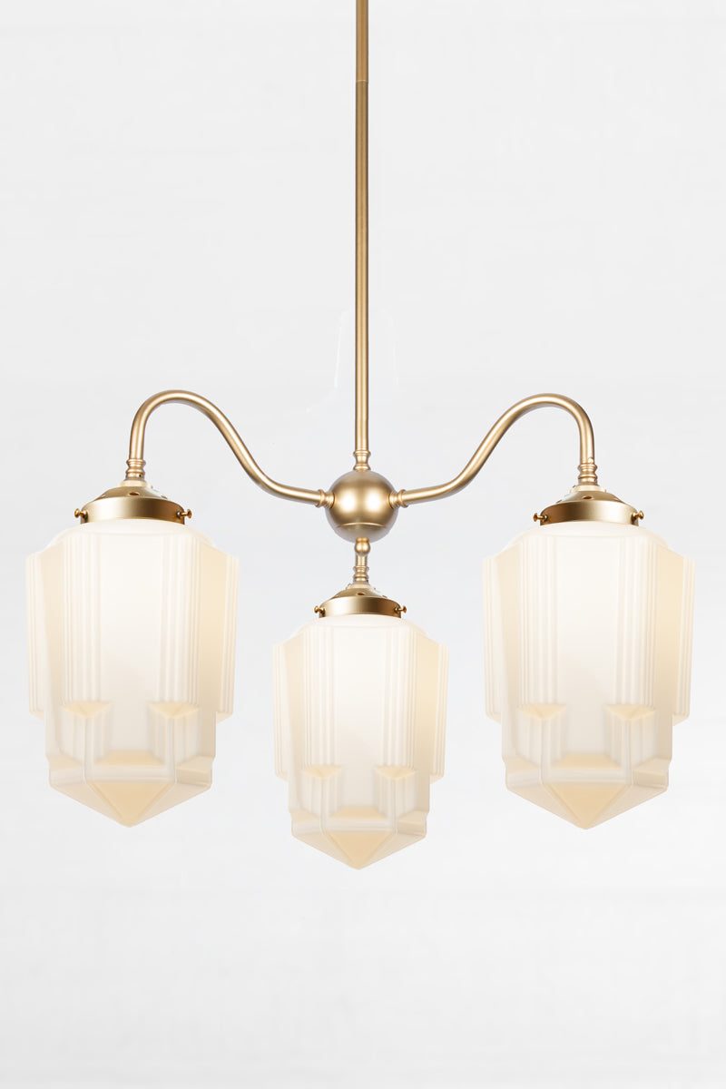 Art Deco opal glass Tivoli shades paired with a gold/brass gooseneck chandelier fixture. 