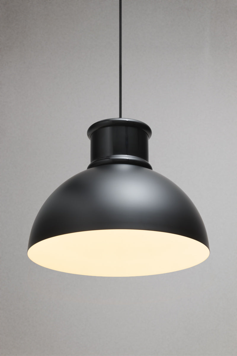 Black industrial dome pendant light with matt black metal shade and warm downward illumination suspended from a black fabric cord.