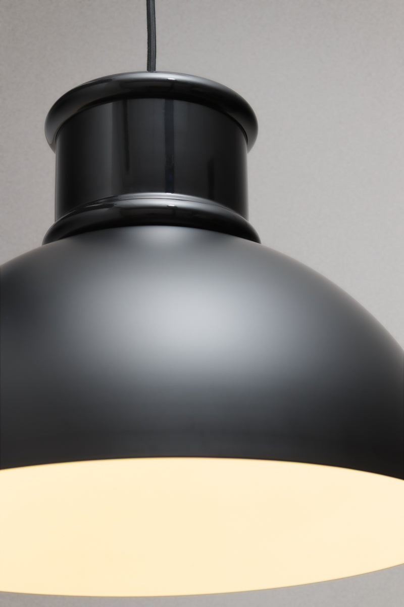Close-up of the matt black industrial dome pendant light highlighting the metal shade and warm illuminated interior.