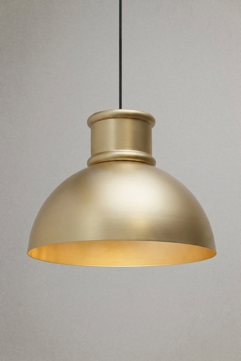 Brushed brass industrial dome pendant light with warm downward illumination suspended from a black fabric cord.