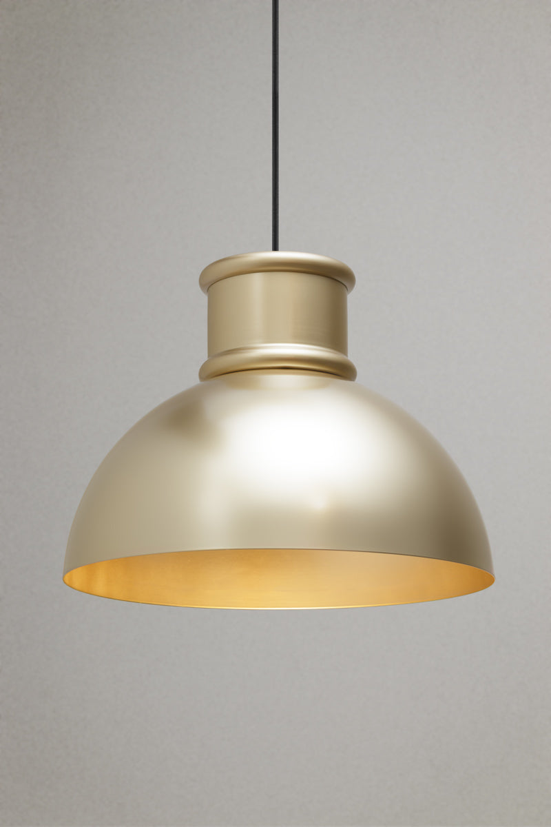 Brushed brass industrial dome pendant light with warm downward illumination suspended from a black fabric cord.