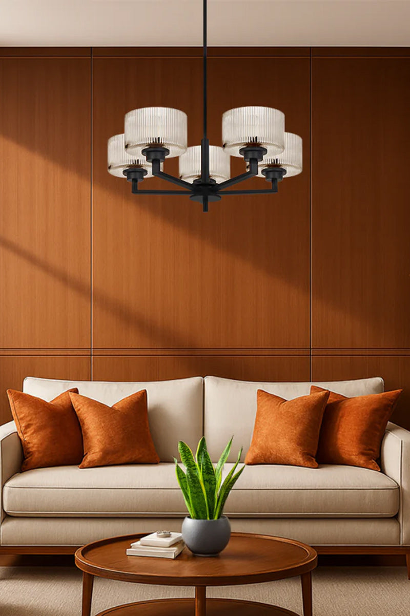 Black 5 light chandelier with clear reeded open glass shades in a burnt orange toned living space. 