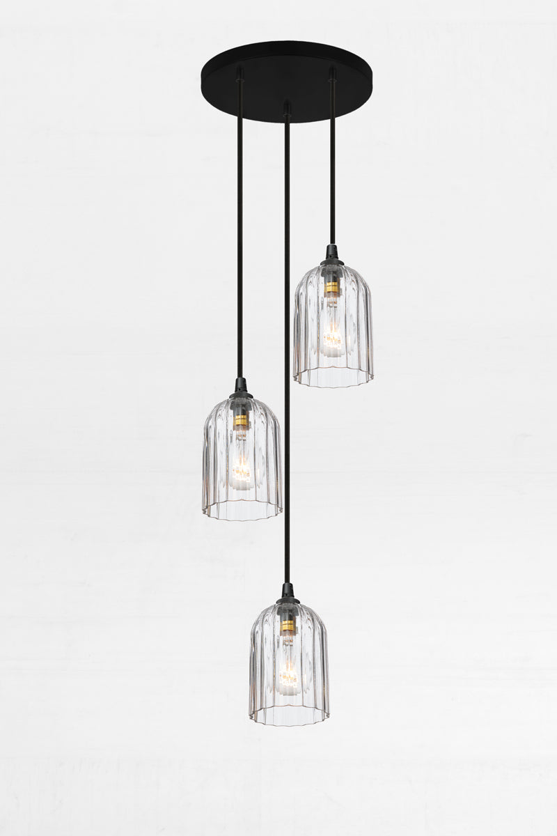 Three fluted clear glass shades, paired with a black circular ceiling rose and cords. 