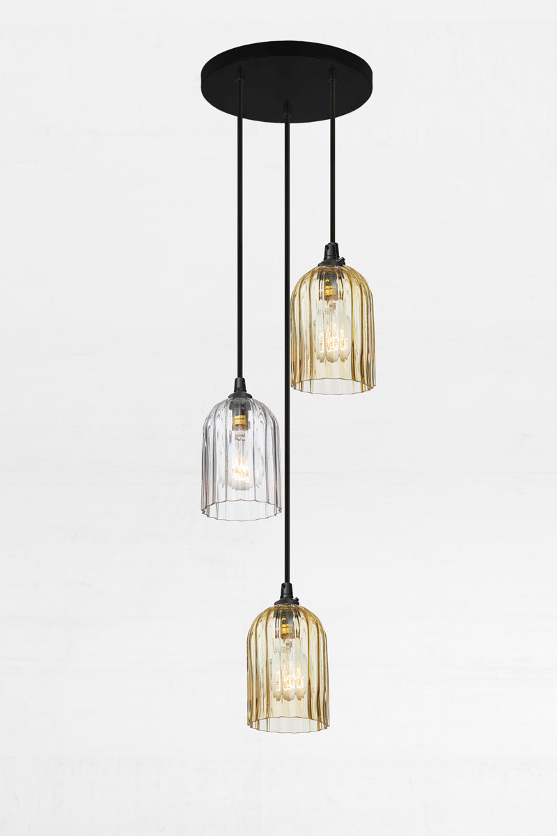 Fluted glass shades in amber and clear, paired with a black circular ceiling rose and cords. 
