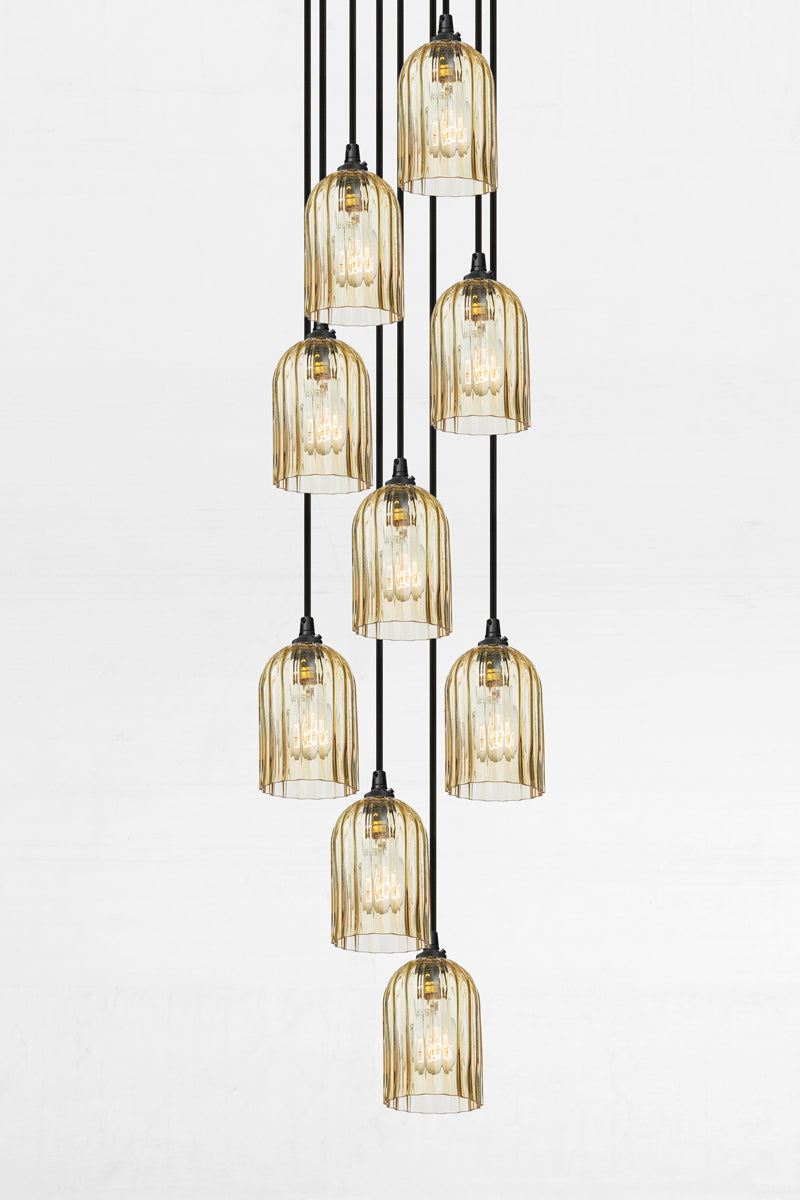 Nine fluted amber glass shades, paired with a black circular ceiling rose and cords. 
