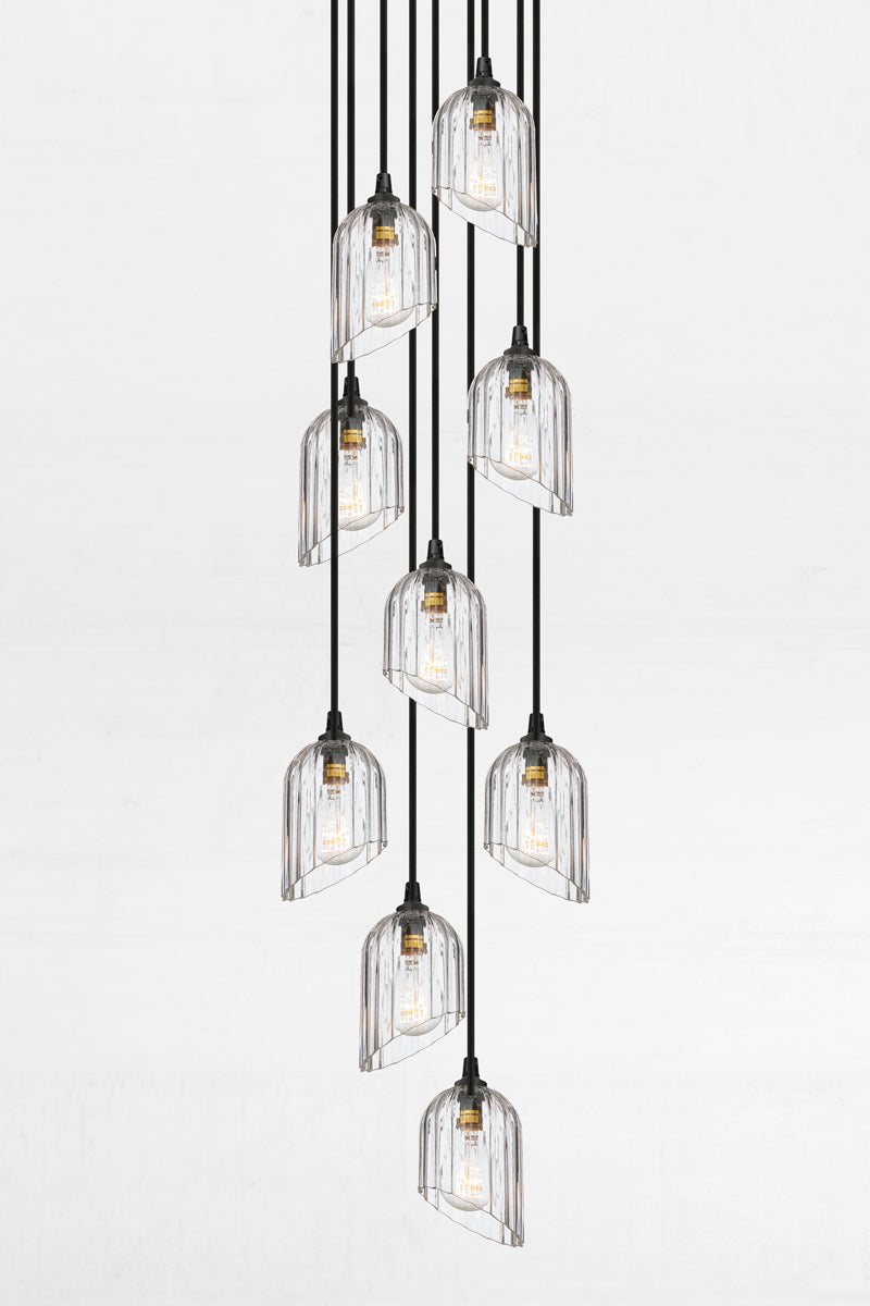Nine fluted clear glass shades with an angled cut detail, paired with a black circular ceiling rose and cords. 